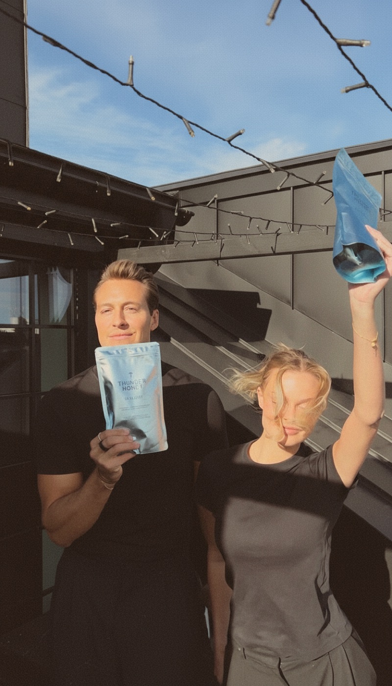 The two founders on a sunlit rooftop, both holding up the silver Thunder Honey Daylight pouch